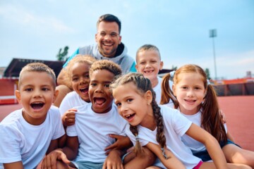 Group of happy kids and their PE teacher during sports training at the stadium.; Shutterstock ID 2409598951; client: 836; job: picturemaxx; other: susanne.finke@cornelsen.de; purchase_order: picturemaxx
Group of happy kids and their PE teacher during sports training at the stadium.
