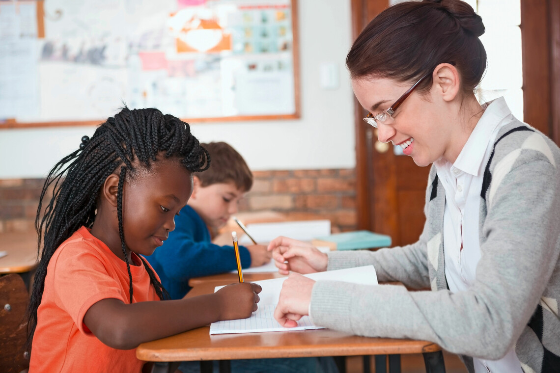 Lehrerin unterstützt Schülerin beim Schreiben