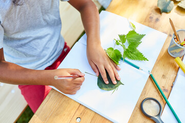 Junge malt Blätter im Sachunterricht