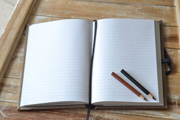 Kreatives Schreiben: Zwei Bleistifte liegen in unbeschriebenem Notizbuch