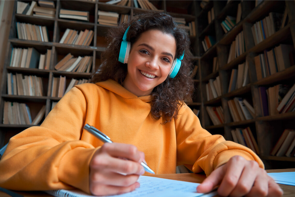 Lächelndes Mädchen mit Kopfhörern in der Bibliothek