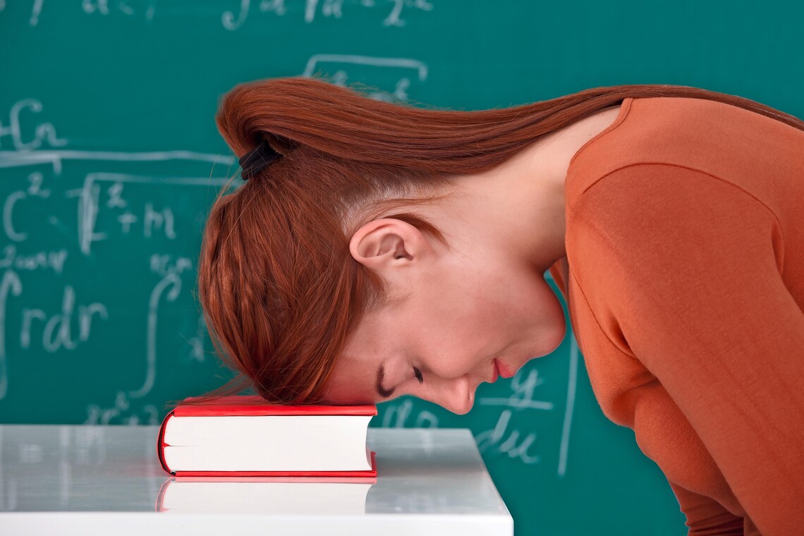 Lehrerin am Pult mit Kopf auf dem Tisch