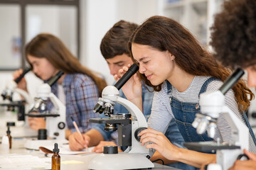 Schülerin schaut durch ein Mikroskop