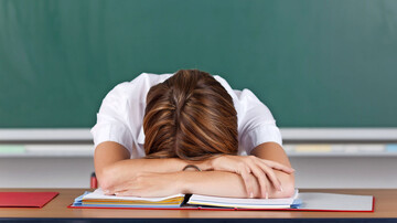 Unterrichtsstörungen: Lehrerin mit Kopf auf dem Pult