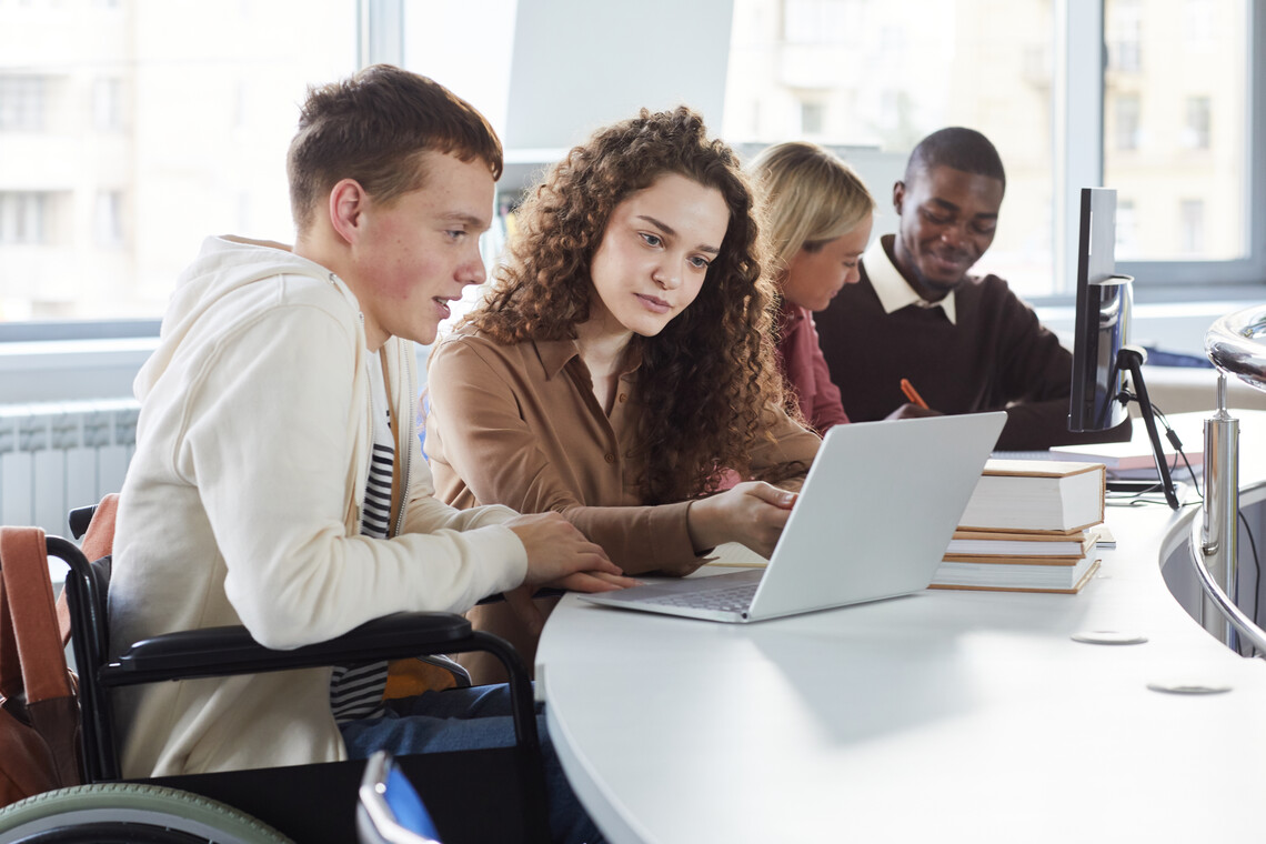 Schüler im Rollstuhl sitzt neben einer Schülerin vor dem Laptop