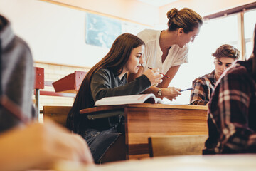 Lehrerin spricht mit 2 Schüler/-innen