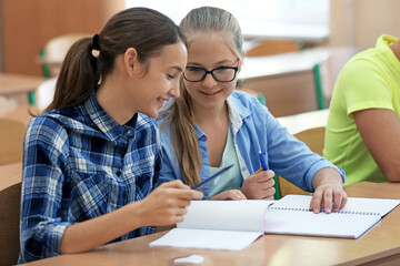 2 Mädchen sitzen im Klassenzimmer und schreiben