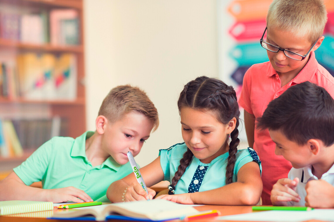 4 Grundschüler sitzen an einem Tisch