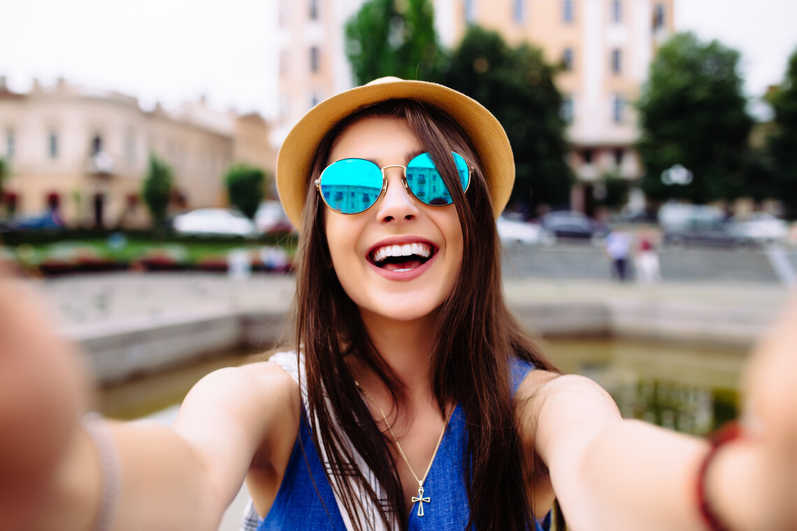 Frau mit Sonnenbrille lacht in die Kamera