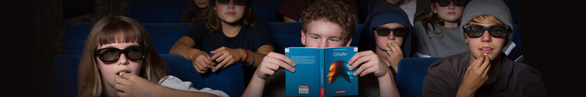 Ein Schüler liest im Kino Othello während andere mit 3D-Brillen Popcorn essen