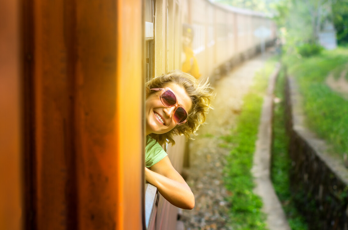 Lächelnde Frau lehnt sich aus einem Zug