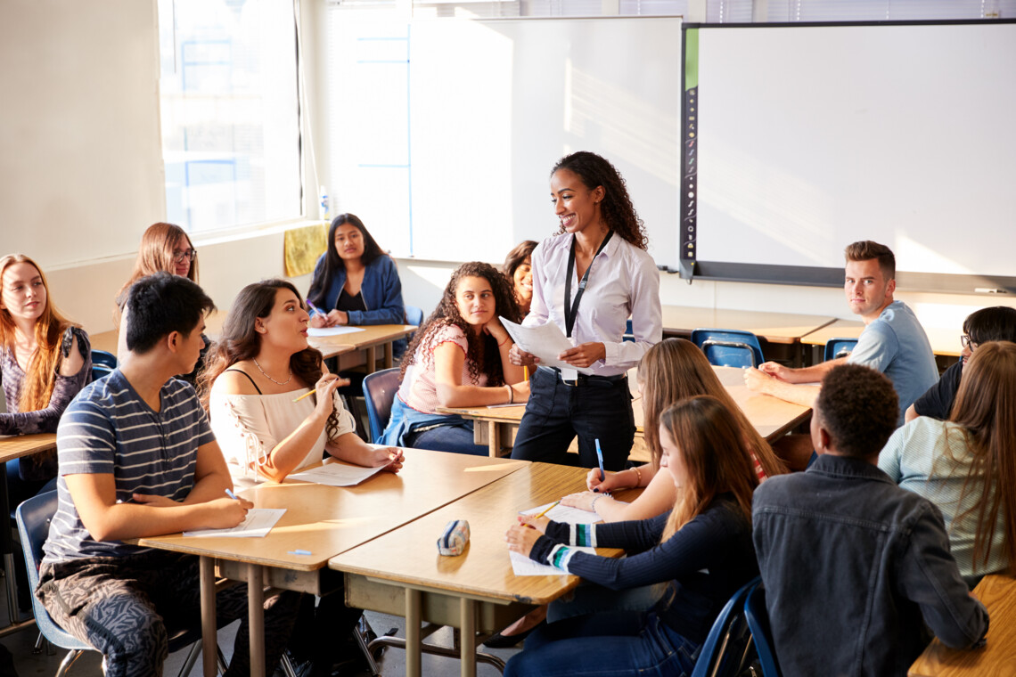 Female High School Teacher Standing By Student Table Teaching Lesson; Shutterstock ID 1332840581; po: ; purchase_order: picturemaxx