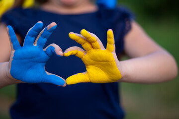 Blau und gelb bemalte Kinderhände die ein Herz formen. 