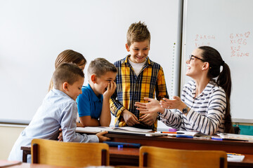 3 Grundschüler/-innen mit ihrer Lehrerin im Matheunterricht