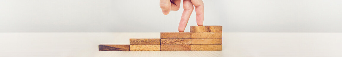 Zwei Finger auf einer Treppe aus Holzbausteinen