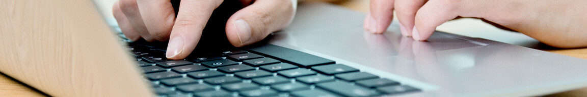 Zwei Hände auf der Tastatur eines Laptops