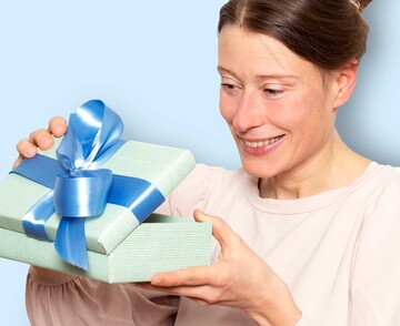 Ein Frau öffnet eine Geschenkbox mit blauer Schleife.