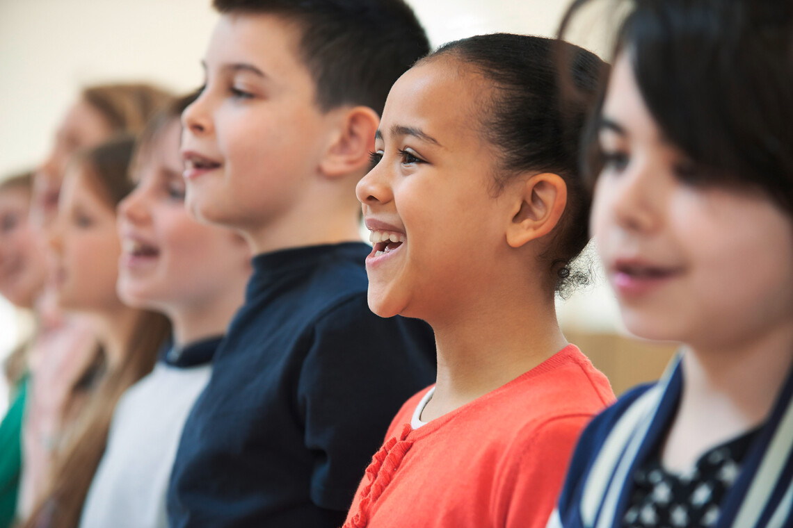 Schüler*innen stehen in einer Reihe und singen