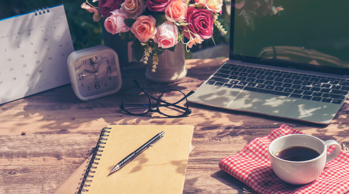Tisch mit Laptop und Schreibtisch und Blumenstrauß