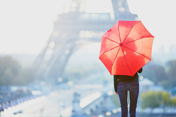 Frau mit rotem Schirm vor dem Eiffelturm