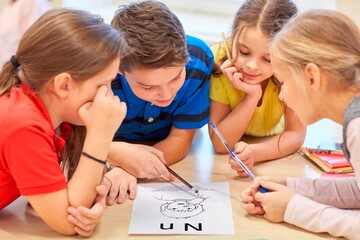 Eine Gruppe von Kindern beugt sich über eine Karte mit Bild und den Buchstaben N und n.