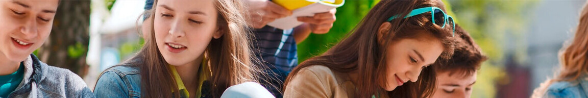 Gruppe von Personen im Freien, einige tragen Sonnenbrillen und lesen oder betrachten etwas.